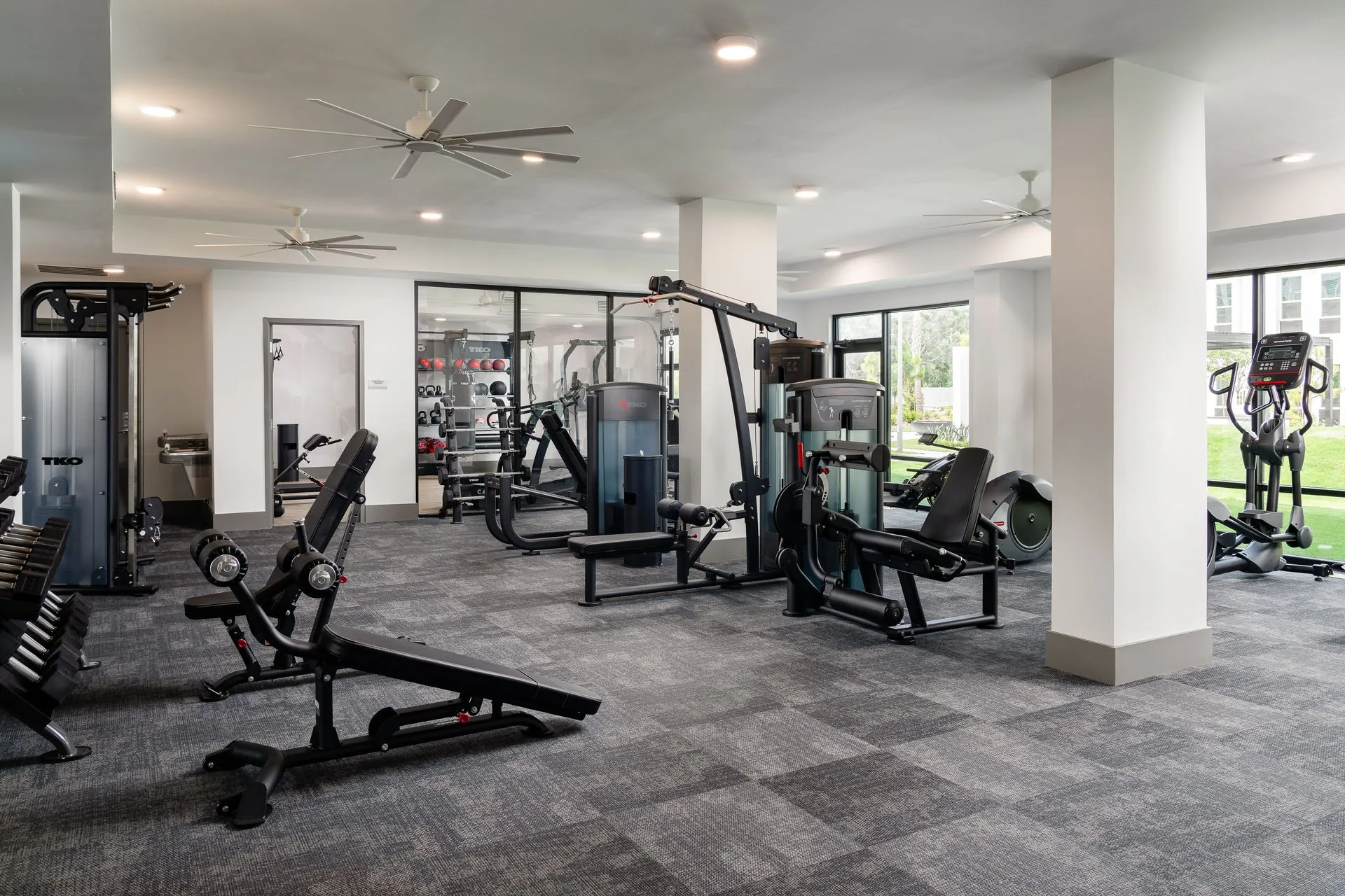 TKO strength floor in a Lutz, Florida apartment gym: functional trainer, dumbbells, benches and selectorized machines