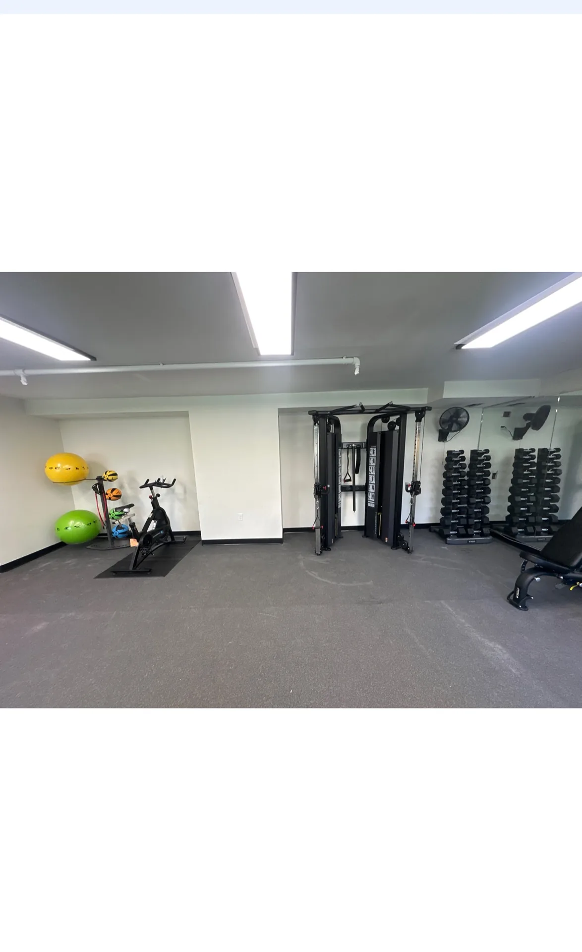 Indoor cycle, stability balls and a functional trainer beside dumbbell racks at a Nottingham, Maryland apartment gym