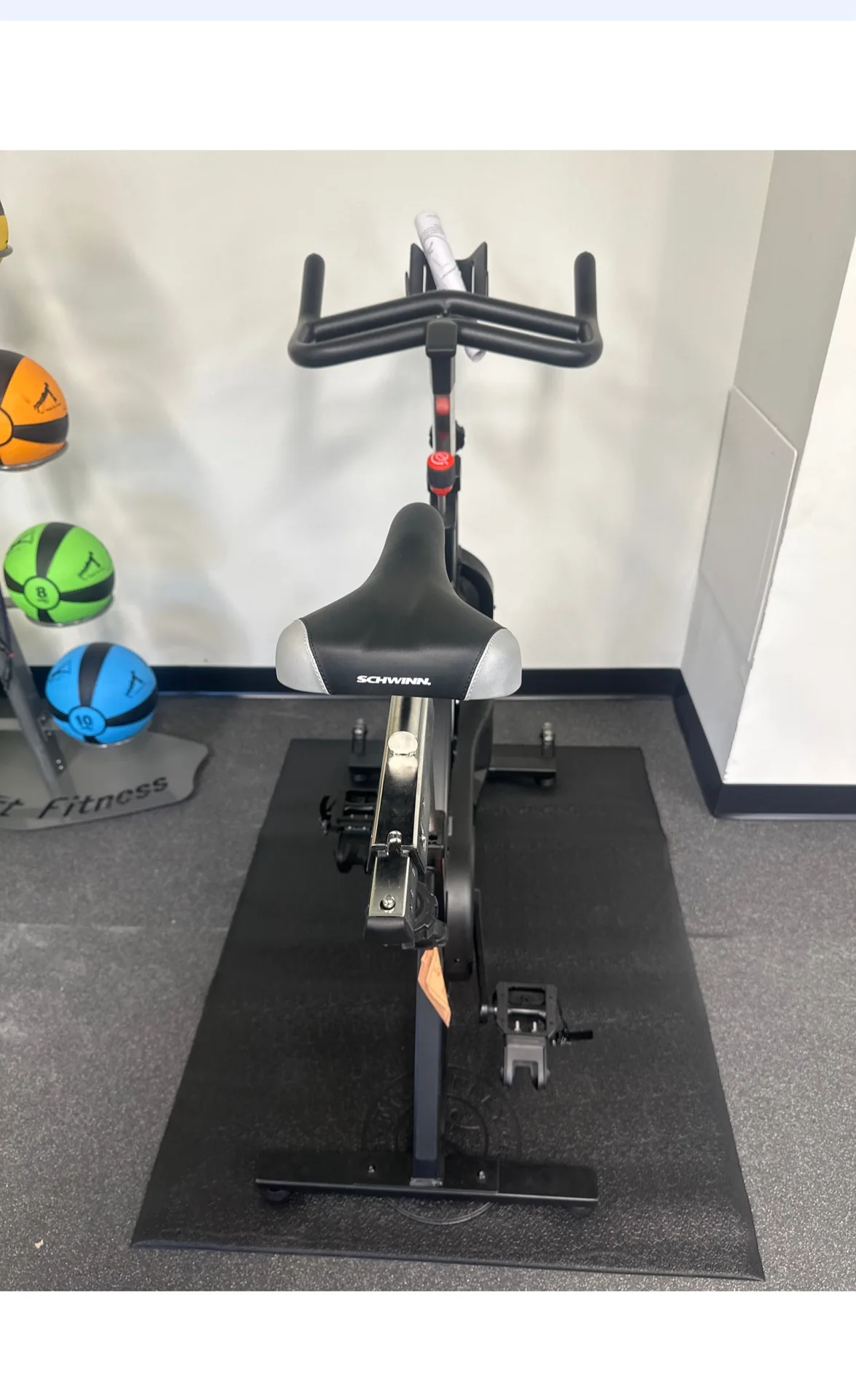 Indoor cycle on a mat beside a wall rack of medicine balls at a Nottingham, Maryland apartment gym