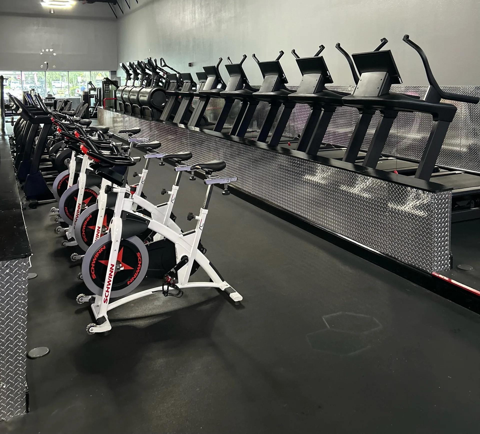 Rows of treadmills, stair climbers and indoor cycles under exposed ductwork in an Ormond Beach, Florida health club