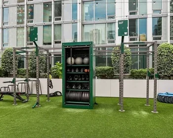 Courtyard outdoor gym on turf with a multi-station rig and storage cabinet