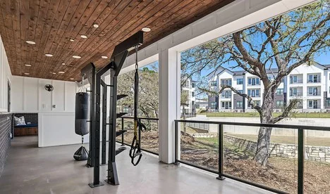 Covered patio training area with a functional rig and heavy bag under a timber ceiling