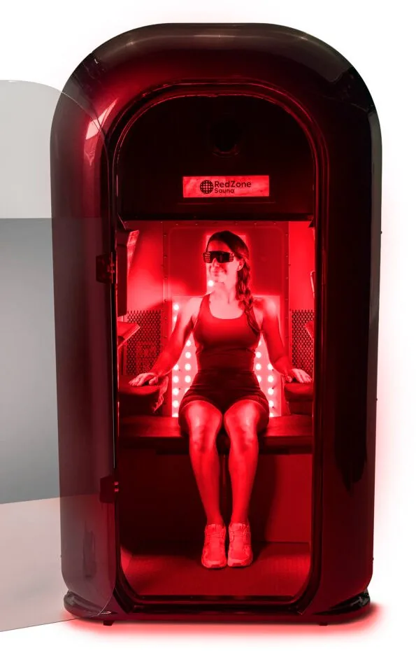 Full-body red light therapy pod with the door open, showing the seated position under red LED panels