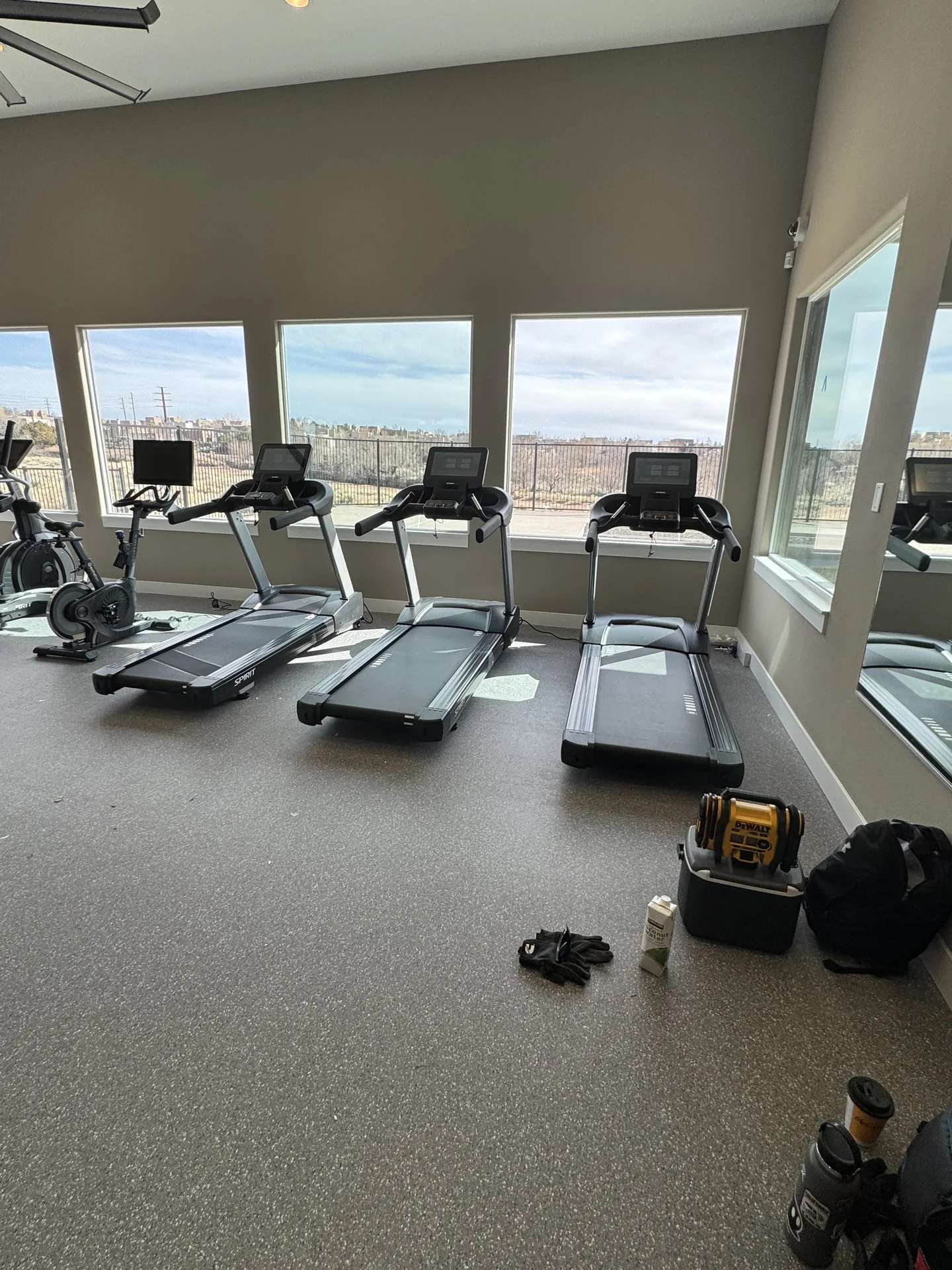 Cardio row part-way through installation at a Santa Fe apartment gym, hand tools and packing still on the floor