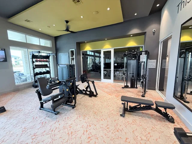 Matrix Versa leg machines, a bench and a storage rack by glass doors to a clubroom in Spring, Texas