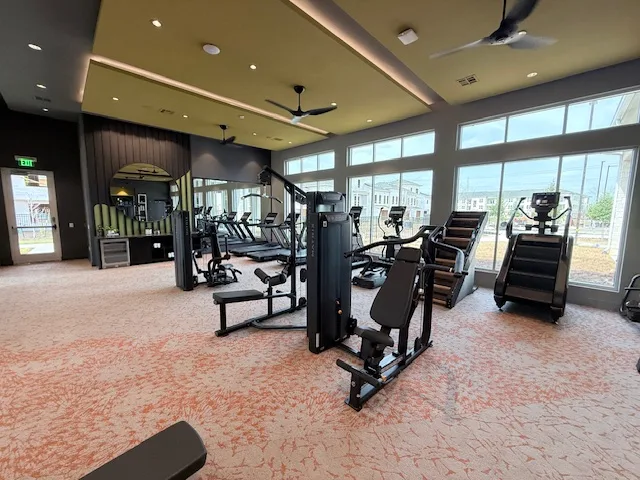 Strength machines, a StairMaster stair climber and cardio under a tray ceiling in a Spring, Texas apartment gym