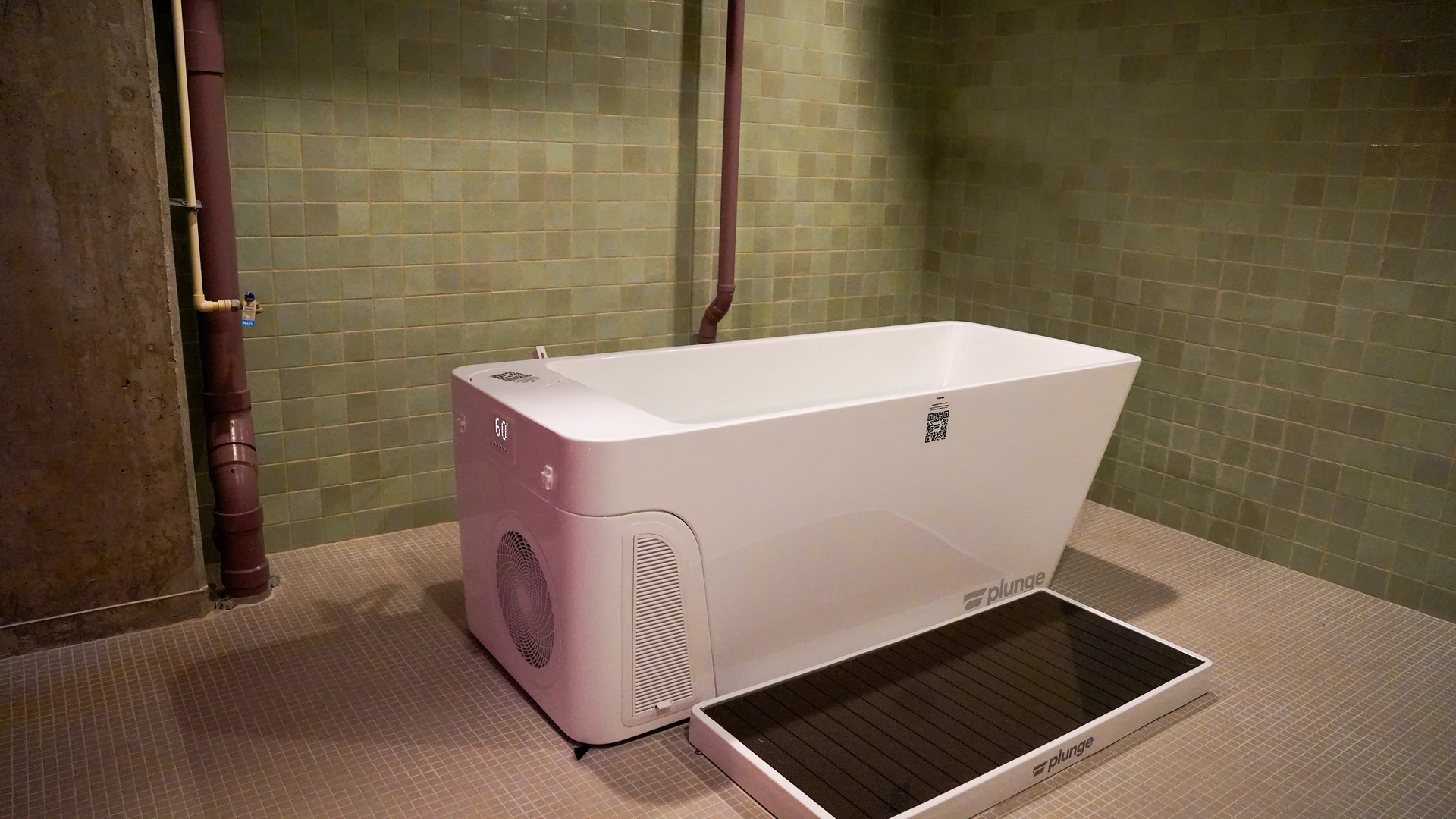 A Plunge-branded cold plunge tub and chiller unit in a tiled recovery room