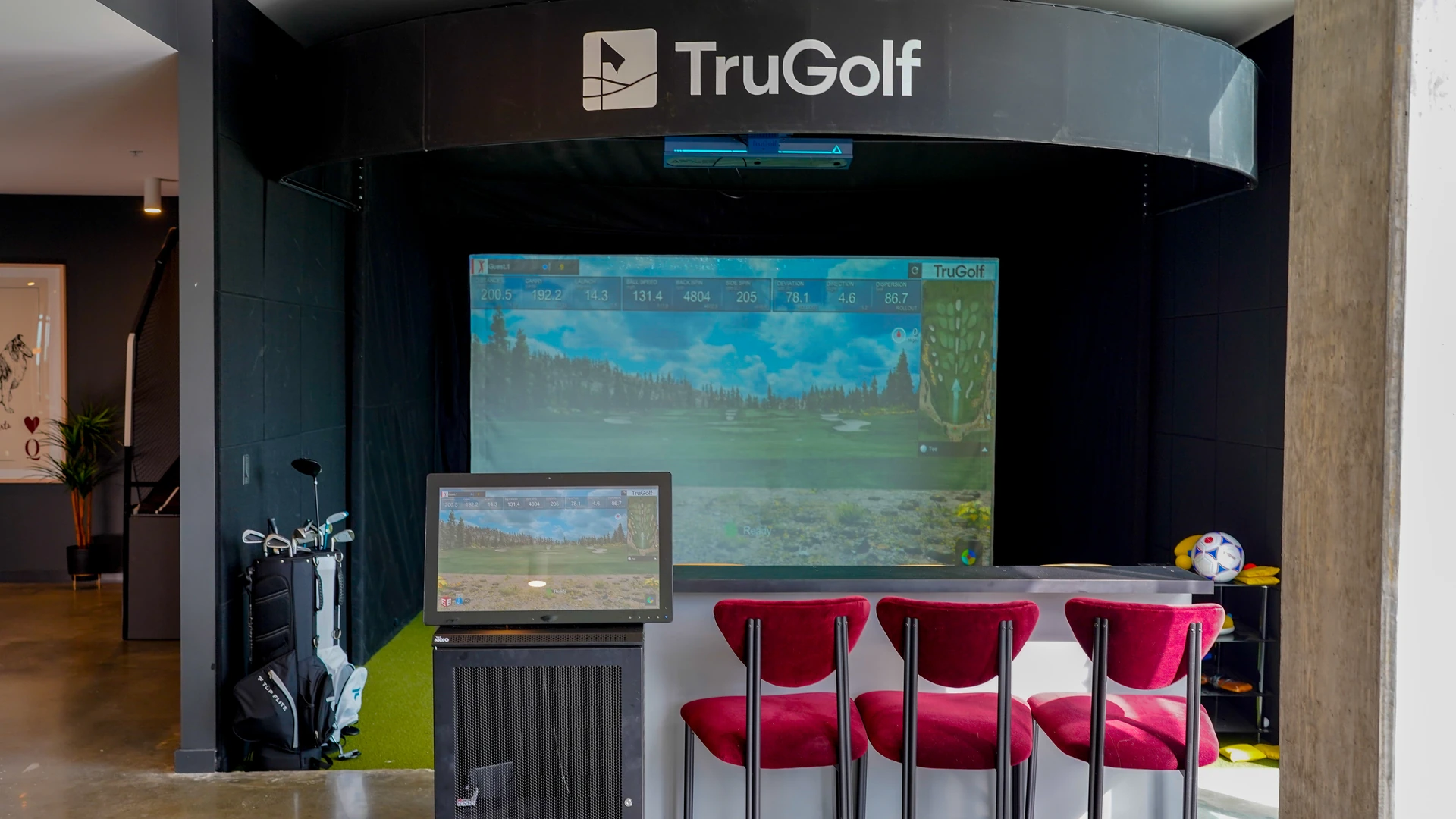 TruGolf golf simulator screen and bar-height seating in a student housing amenity lounge