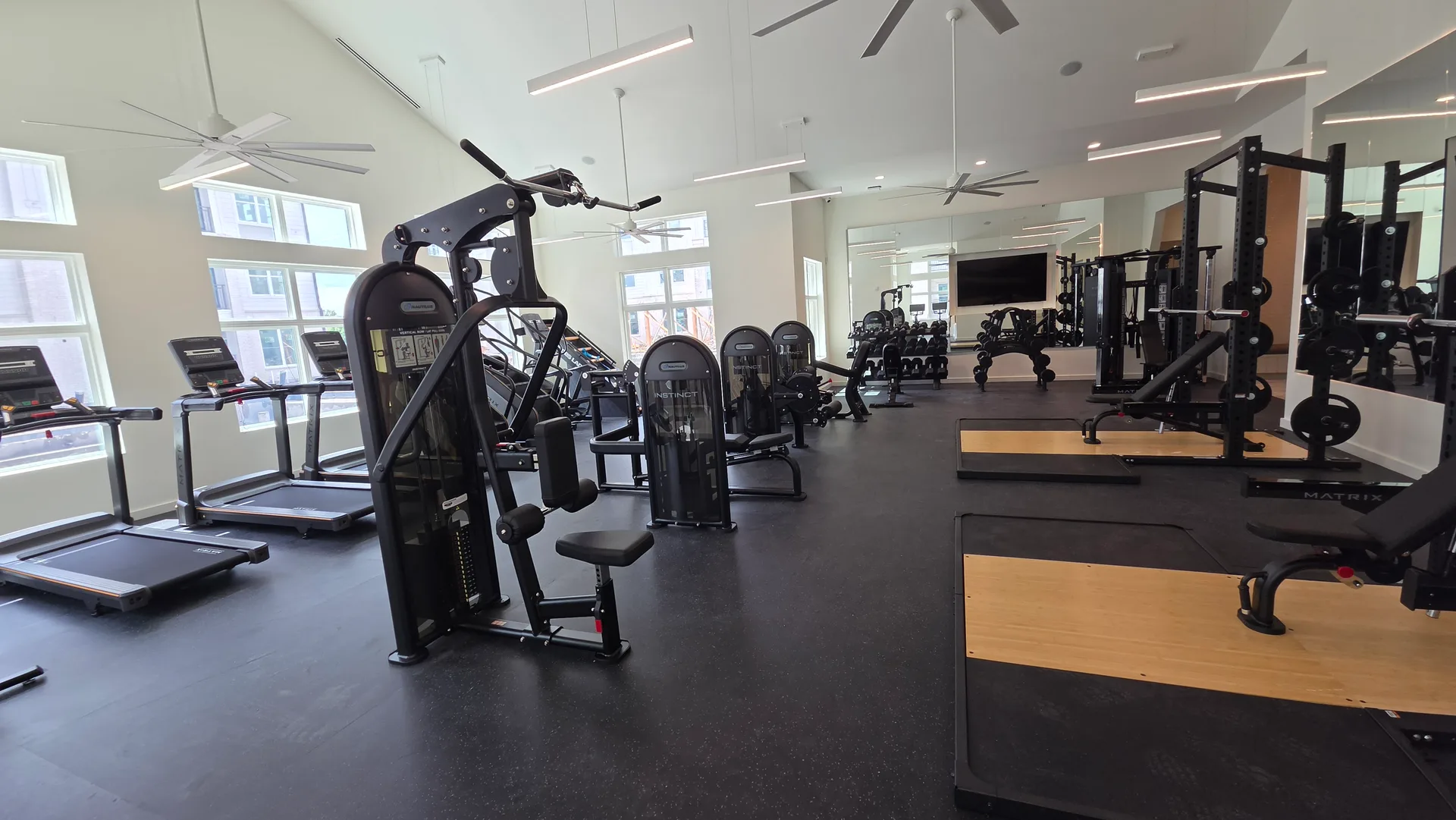 Instinct selectorized strength and treadmills under a vaulted ceiling with fans in a Webster, Texas apartment gym