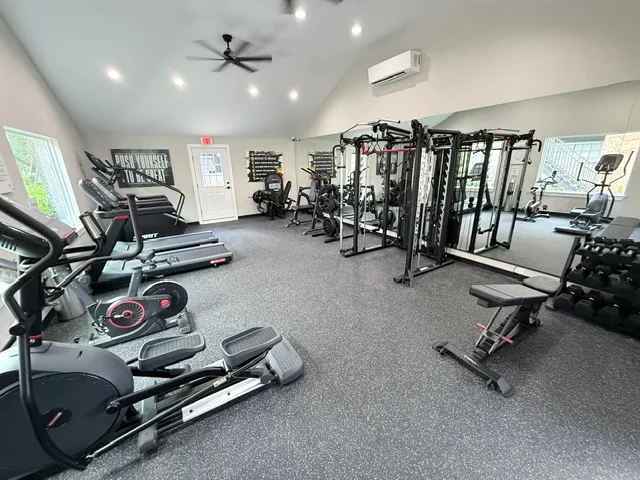 Ellipticals, treadmills, a rack-and-cable system and dumbbells under a vaulted ceiling in The Woodlands, Texas